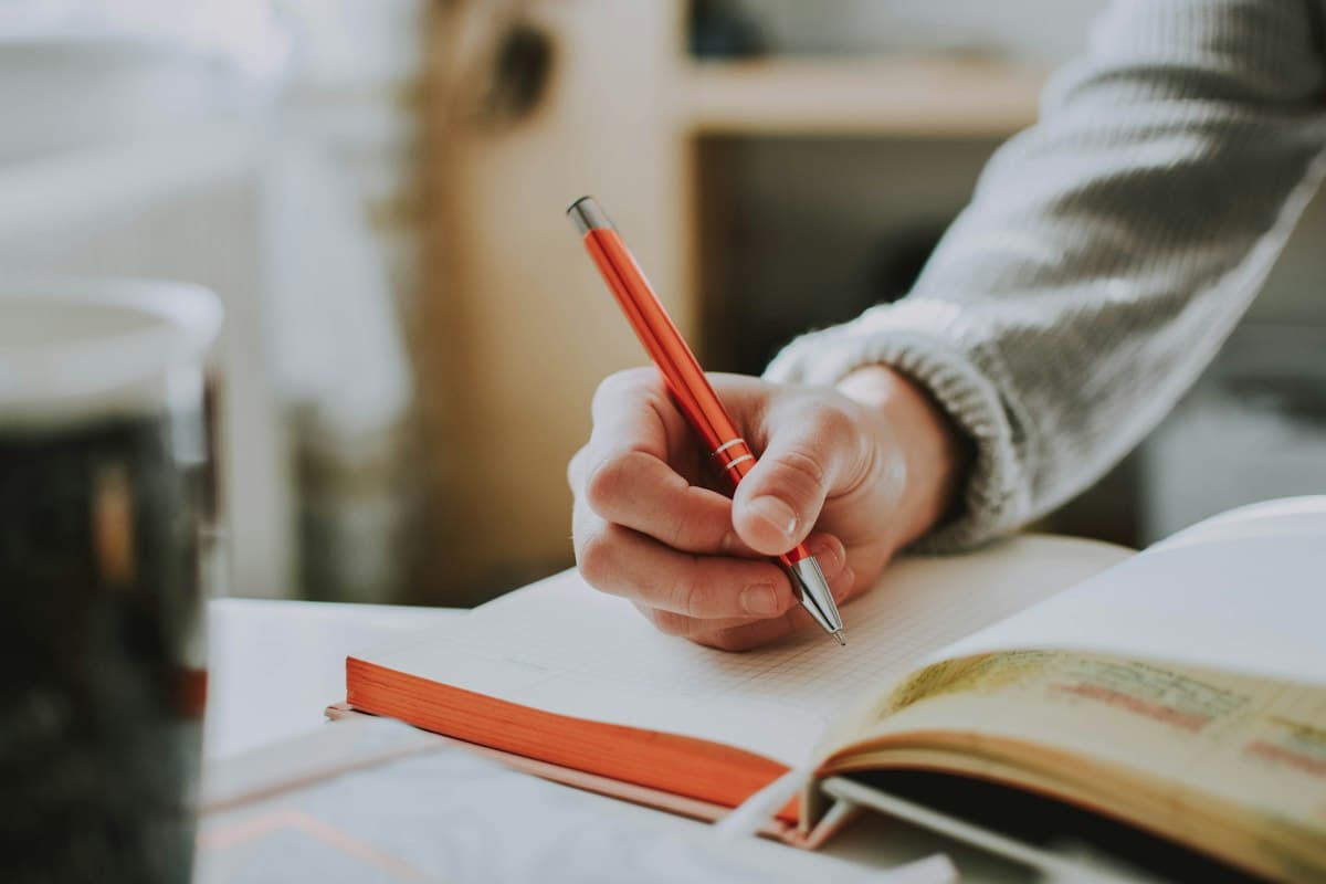 Hand writing in an open notebook in soft daylight