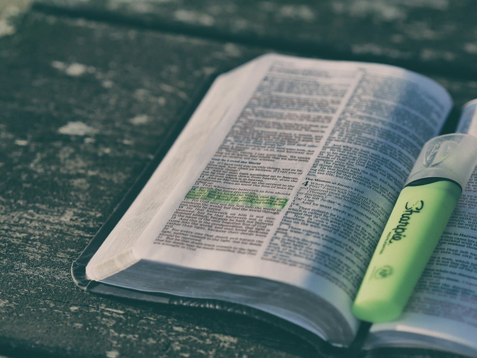 Open Bible with a passage highlighted in green and a highlighter resting on the page