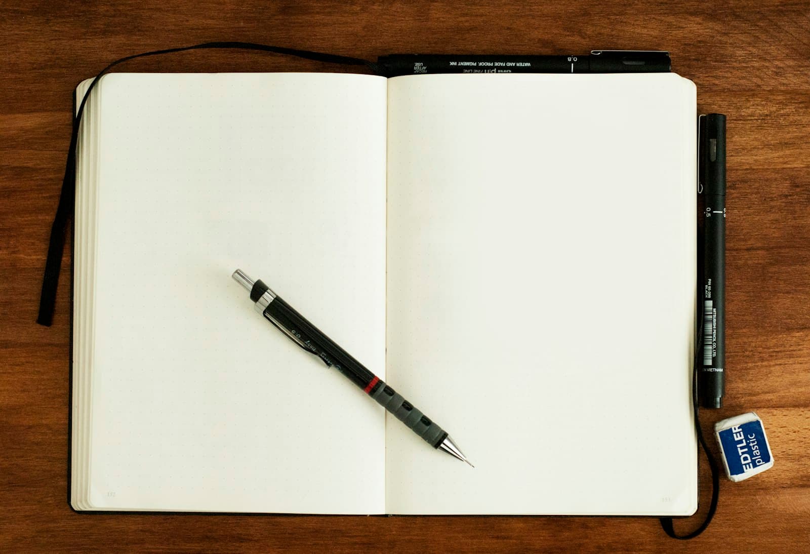 Blank open notebook with a pen on a wooden desk